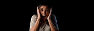 Latina woman with hands on cheeks and a screaming expression, black background
